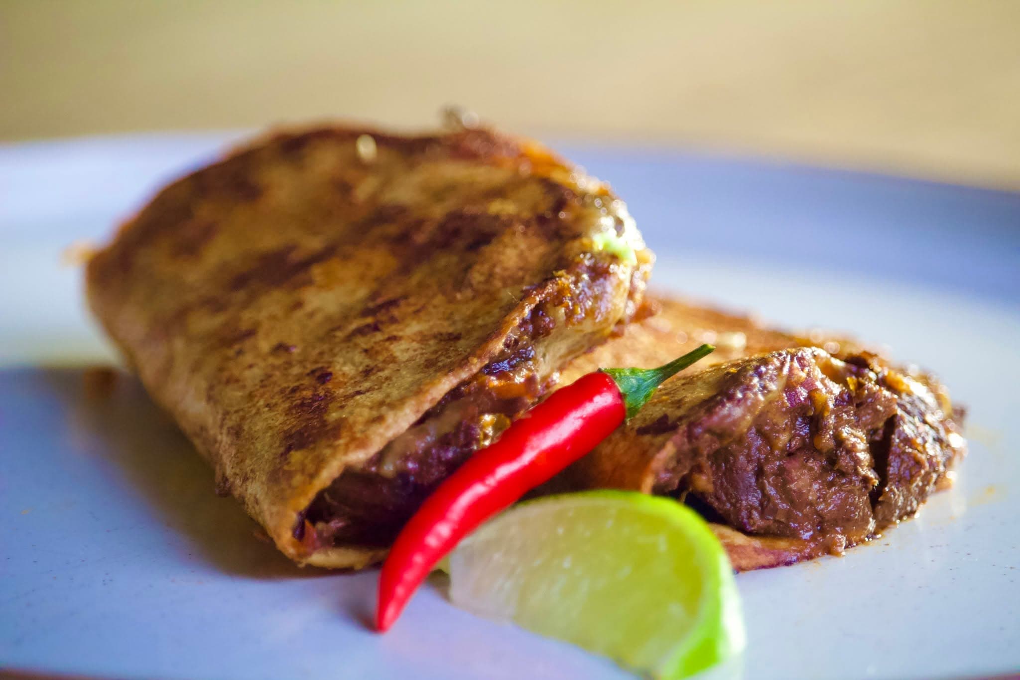 Slow-braised birria tacos with melted cheese, fresh lime, coriander and chilli